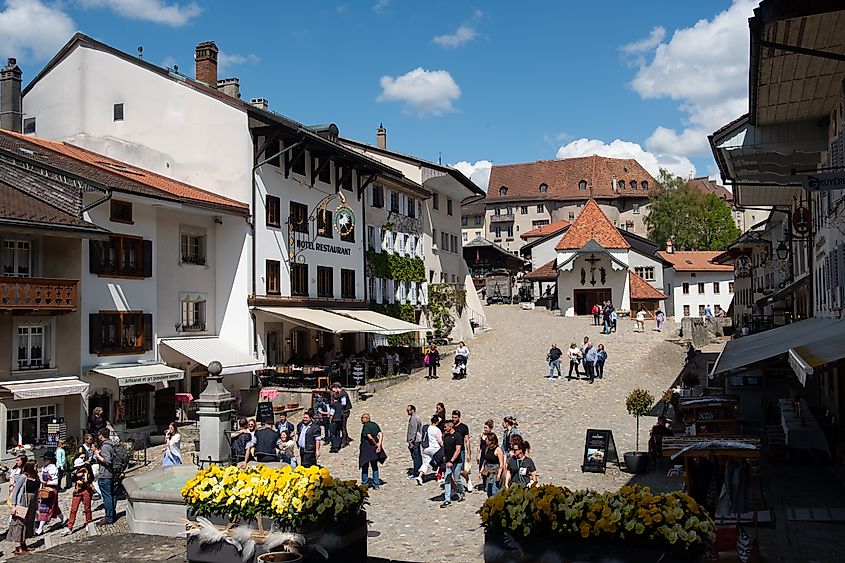 Tourists walking through the cobblestone square of Gruyères, Switzerland