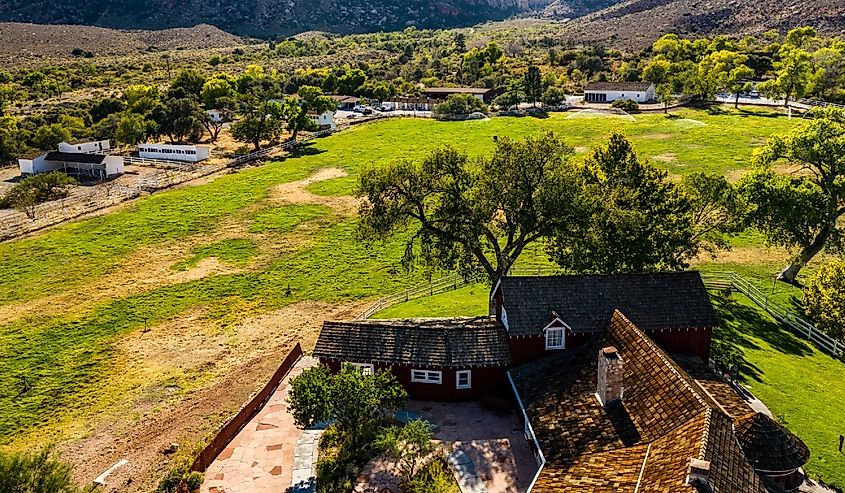 Beautiful view of famous Spring Mountain Ranch State Park near Las Vegas and Red Rock Canyon, Nevada during autumn with pink and red rock mountains, blue sky, green trees and grass, and purple hills