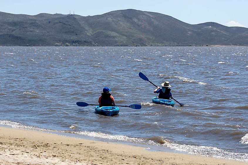 Two kayakers paddling on a windy day close to the beach at Washoe Lake