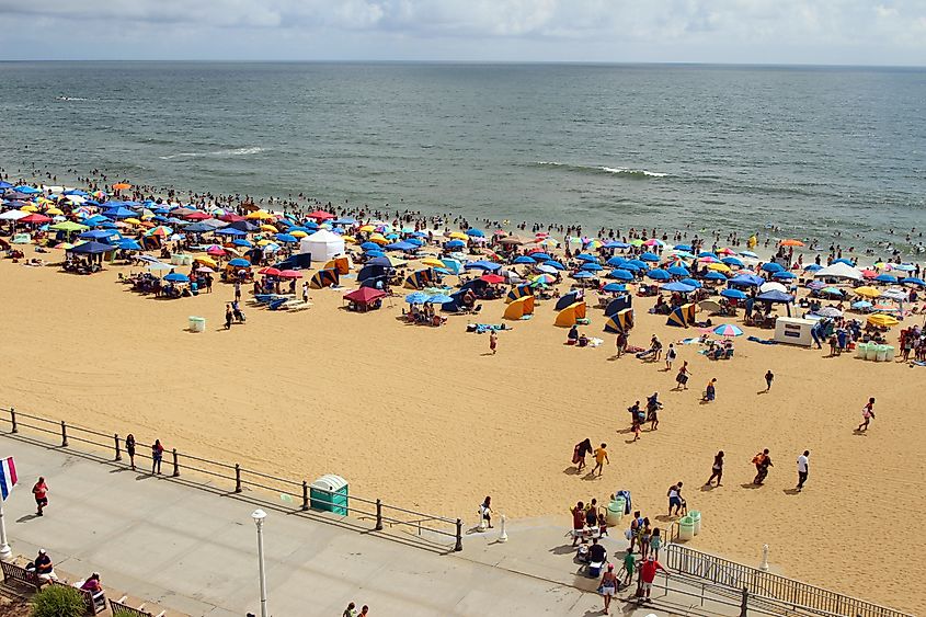 A view of a crowded beach with people relaxing and bathing. Virginia Beach on Independence Day, Fourth of July