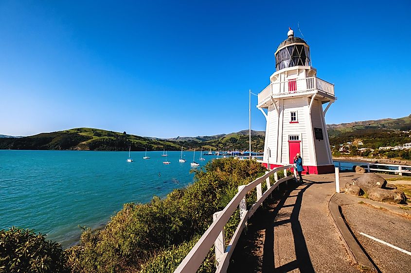Красивый маяк находится в Акароа, Новая Зеландия. Это идеальное место для отдыха. Он популярен среди туристов, туристов и местных жителей. Можно наслаждаться чистым голубым небом, океаном и магазинами.