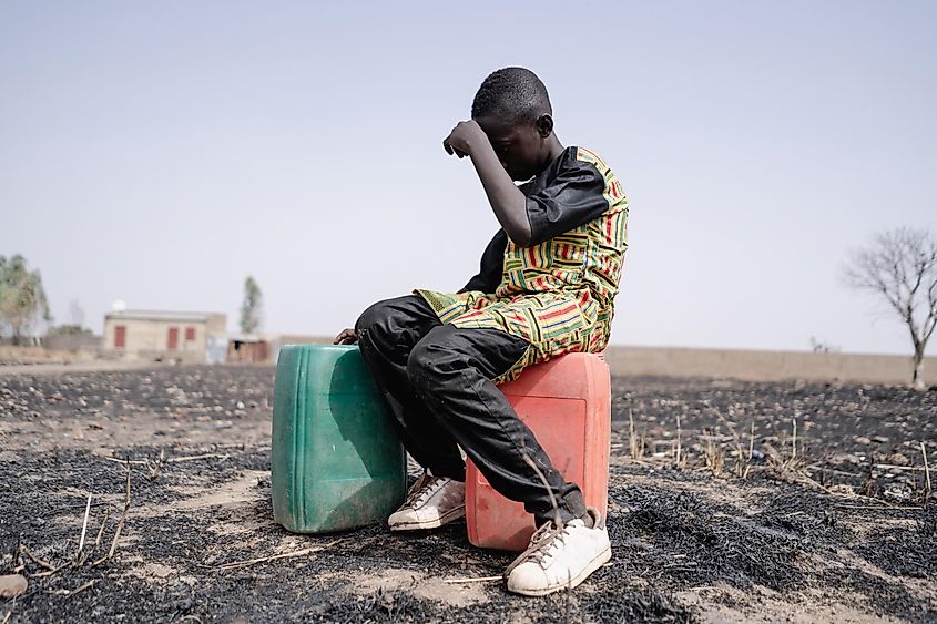 African teenager strained for walking long distance to collect clean water.