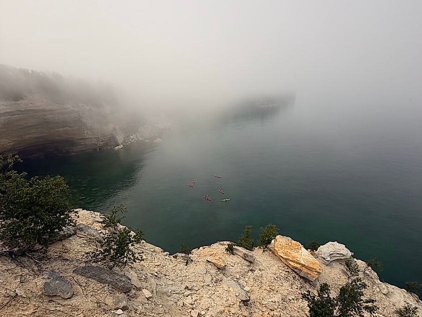 A high angle photo of a group of kayakers as seen from the cliffs above.