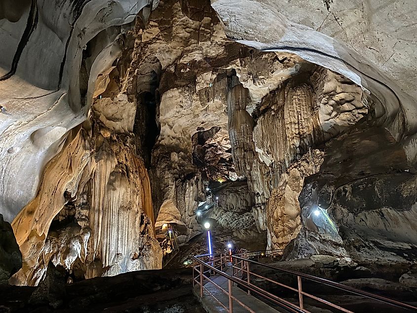 A walkway explores a massive cave illuminated by fixed lights. 