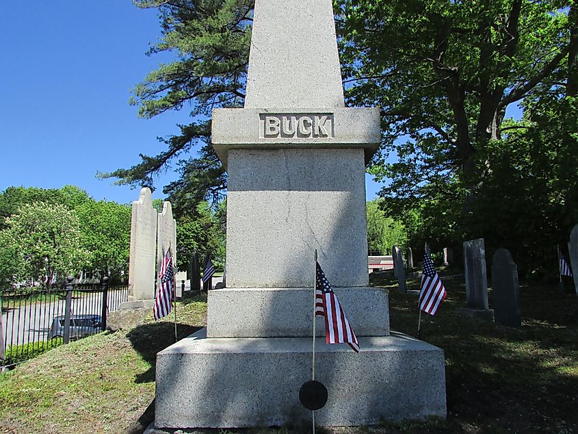 Monument to Colonel Jonathan Buck in the cemetery on Main Street in Bucksport, Maine. According to local legend, Col. Buck condemned a woman to death for witchcraft and she placed a curse on him, saying she would forever stand on his grave. Interestingly, the monument has a stain on it that is in the shape of a human leg and foot. 