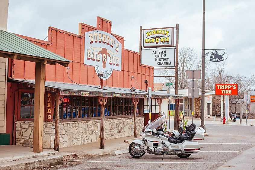 Bandera, Texas - Shops and signs with cars and bikes parked in front.