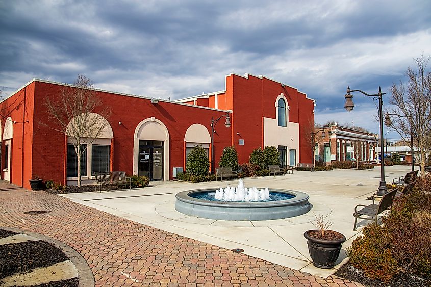 O'Neal Plaza with red brick buildings, black metal fences, bare trees and lush green plants along Veterans Memorial Hwy.