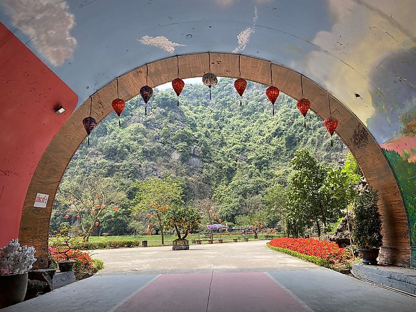 A colorful tunner decorated in traditional Vietnamese lanterns opens onto a forest mountain scene.