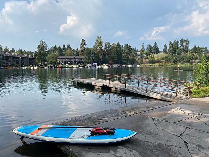 A female paddleboard in a small harbor coming to meet the photographer's docked paddleboard.