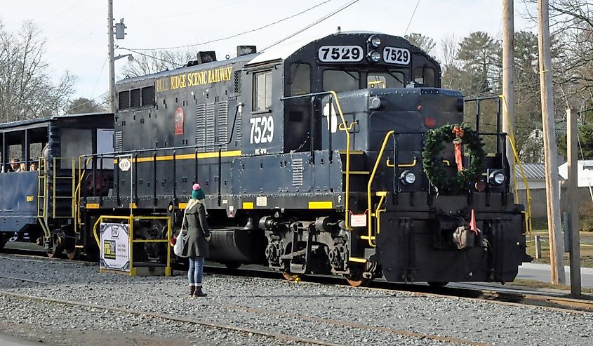 Woman staring at the old remodeled locomotive of Blue Ridge Scenic railway in December in Blue Ridge, Georgia