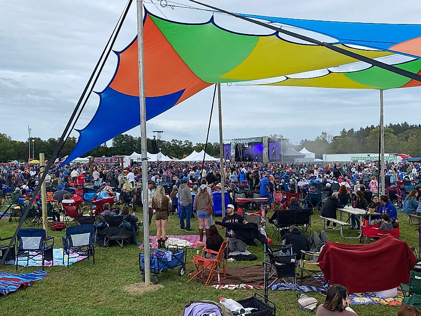 A large crowd gathered on the grass in front of the Main Stage at dusk.