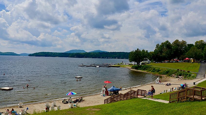 Summer scene at Schroon Lake Beach, showcasing visitors enjoying the sunny weather, sandy shore, and refreshing water.