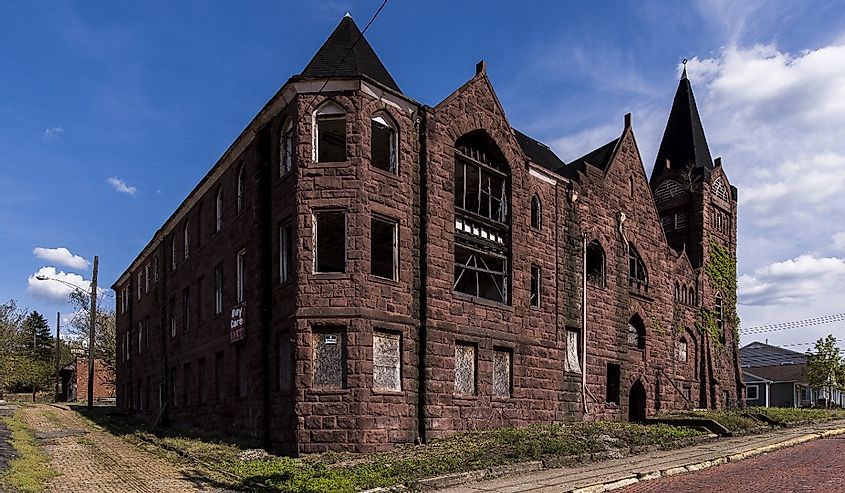 A wide view of an abandoned Baptist Church with a sandstone facade along brick streets in McKeesport, Pennsylvania.