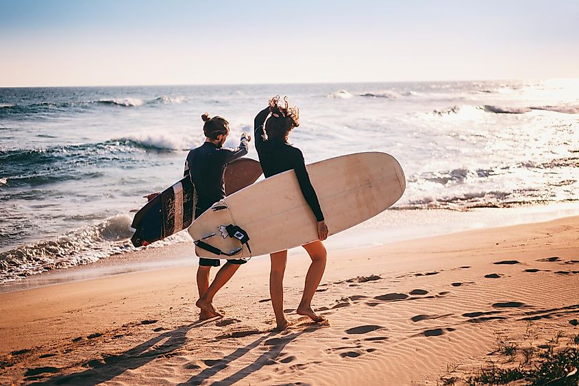 Couple walking along the sandy beach near the ocean at sunset