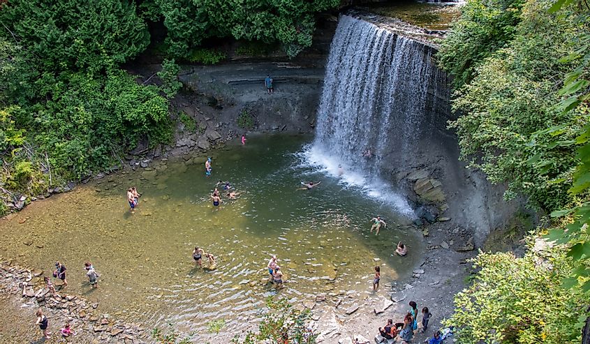 People enjoying the cool freshwater at Bridal Veil Falls on a summer day on Manitoulin Island