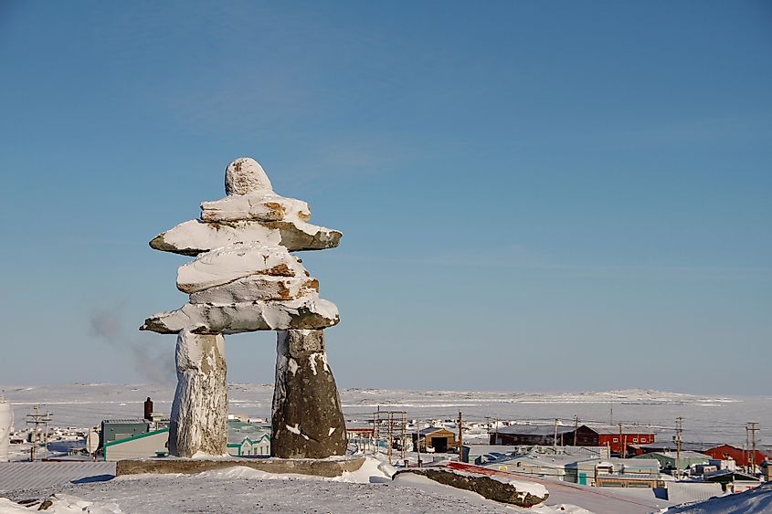 Inuksuk (or spelled Inukshuk) landmark covered in snow found on a hill in the community of Rankin Inlet, Nunavut, Canada