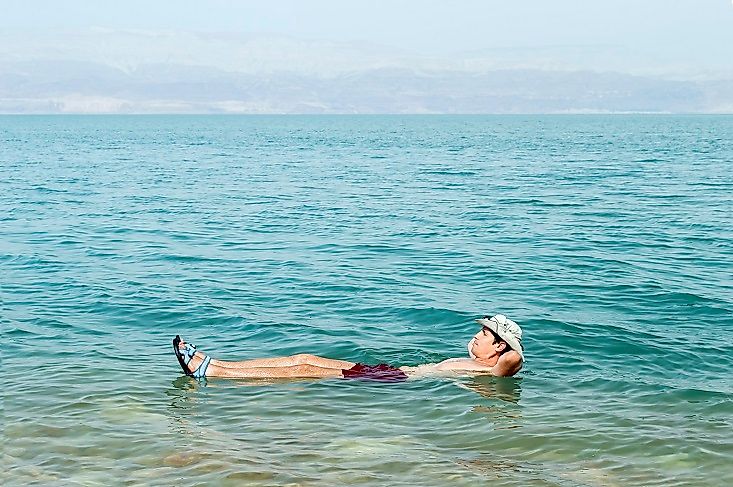 A man floating effortlessly on the surface of the Dead Sea while reading.