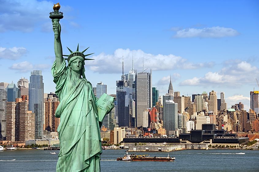 new york city skyline cityscape with statue of liberty over hudson river. with midtown Manhattan skyscrapers and freight sailing ship in usa america.