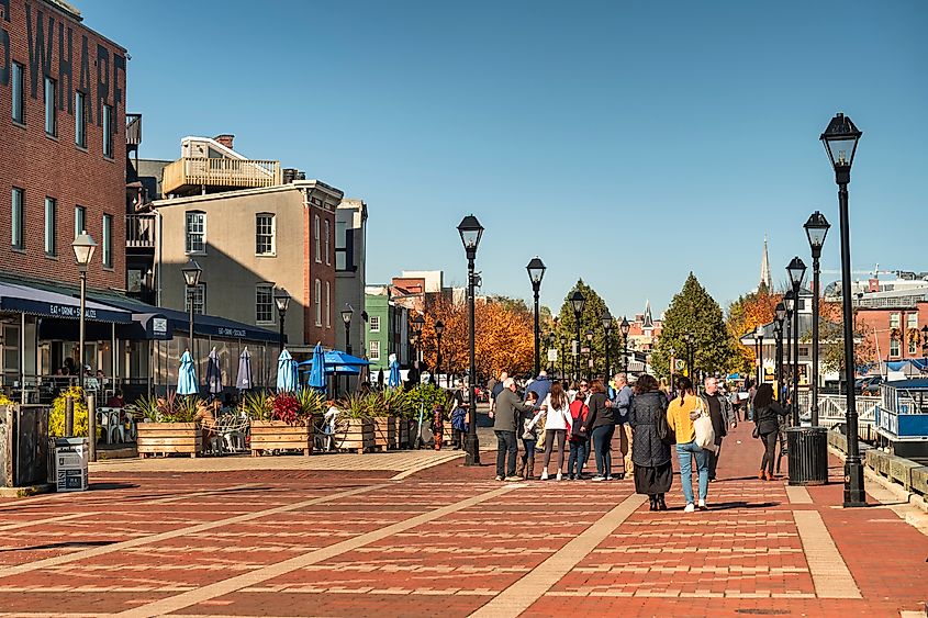 People walk along the boardwalk paths and the chic restaurants and taverns of Fells Point in Baltimore Maryland flowing on the Patapsco River and Chesapeake Bay
