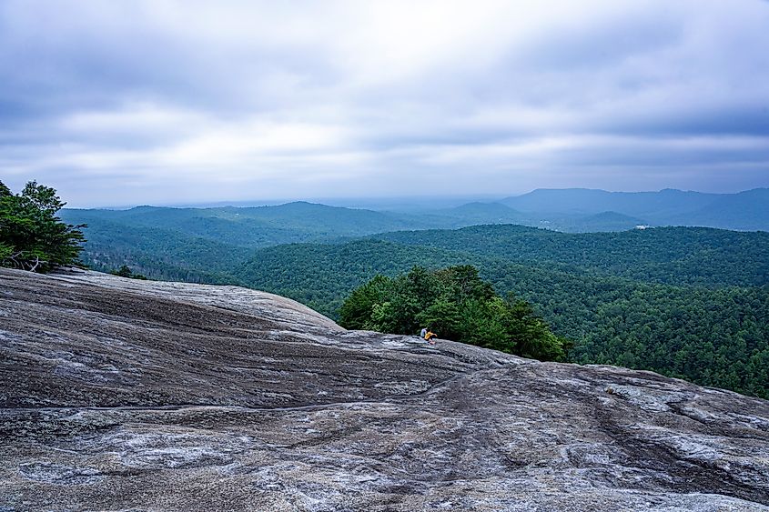 A young couple, man and a woman, sit at the summit of Stone Mountain in North Carolina