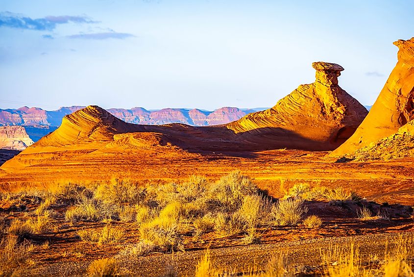 Warm sunset light illuminates Radio Tower Rock rising from desert landscape within Glen Canyon National Recreation Area