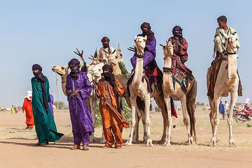 Tuareg people in traditional clothes sitting on camels.