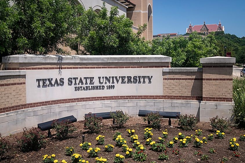 Texas State University welcome sign with Old Main in the distance