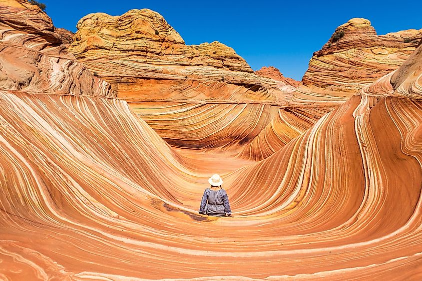 A young girl sits with her back to the camera in the central part in Wave Canyon, North Coyote Buttes, Arizona, USA