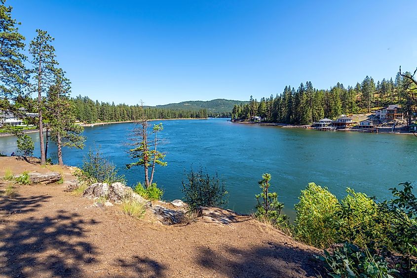 The Spokane River in Post Falls, Idaho, with waterfront homes along the shore near Black Bay park on a summer day