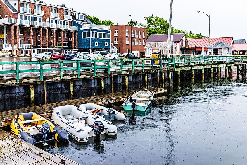 Wooden marina harbor in Castine, USA, during rain, featuring boats and a parking lot in the small village of Maine.