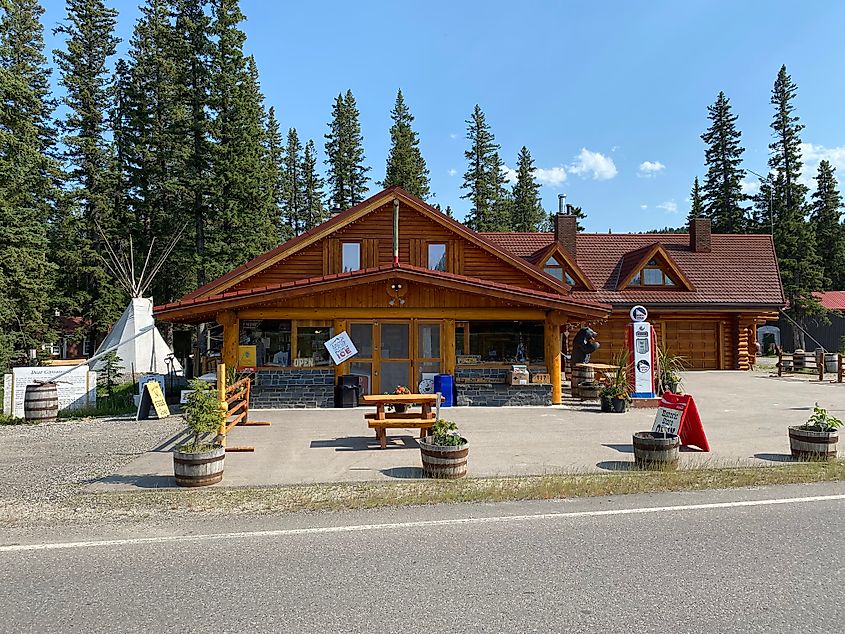 The exterior of a lodge-style general store with a tipi pitched next to it. 