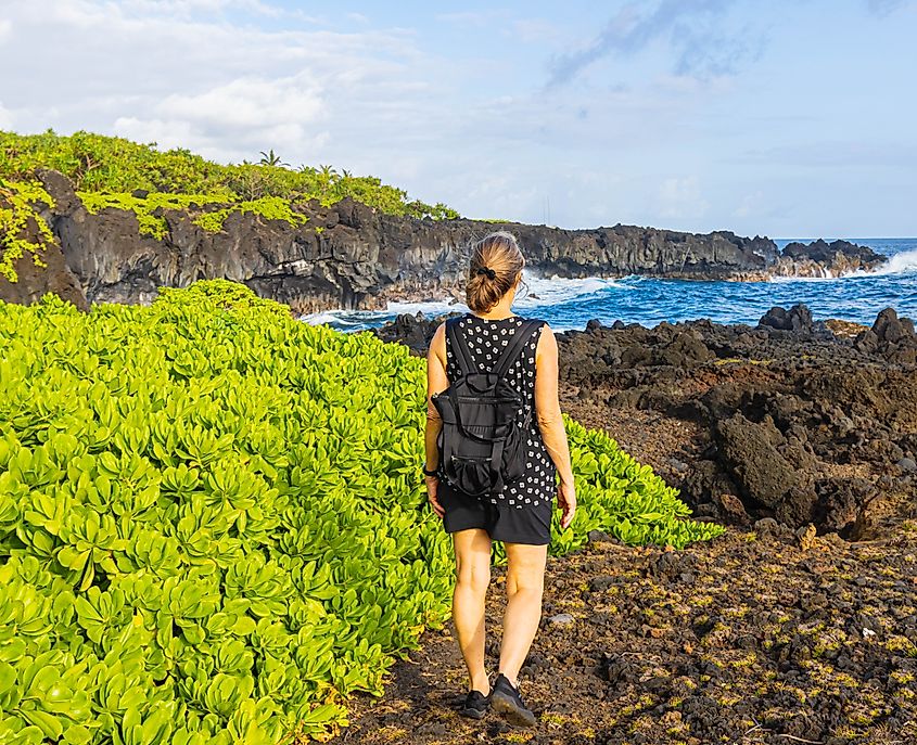 A hiker on the volcanic shoreline of the King's Trail near Kauiau Point, Waianapanapa State Park, Maui, Hawaii.