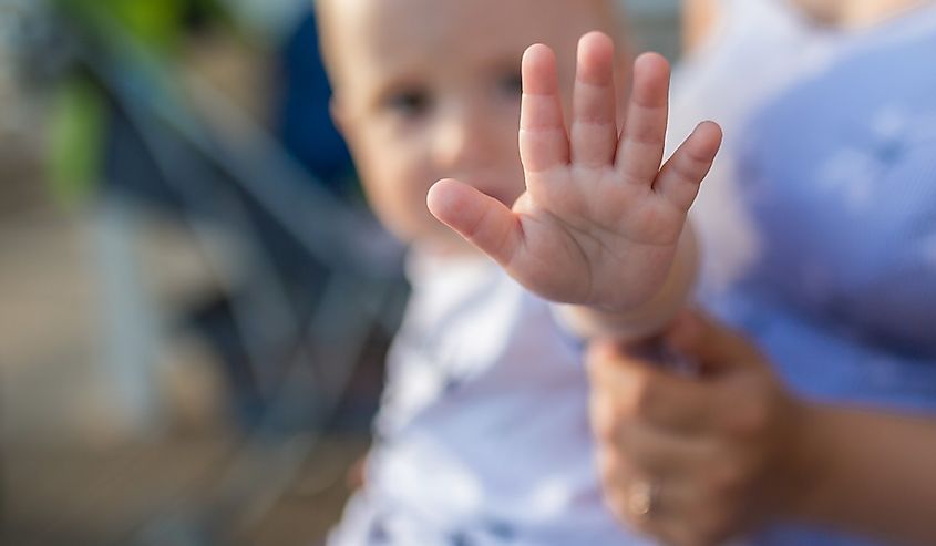 A young boy putting up his hand, to say no, or stop.