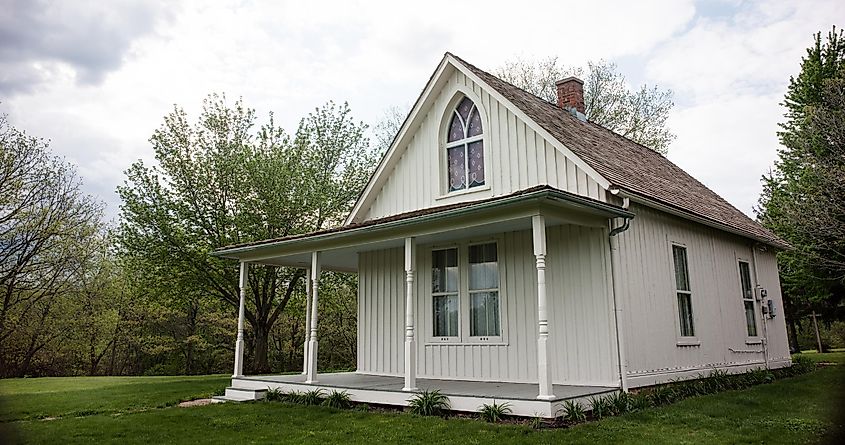 Iconic America Gothic house, made famous by artist Grant Wood, on an overcast day saturated with springtime color.