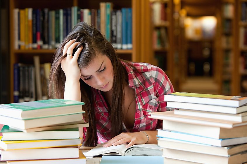 Focused student surrounded by books in a library
