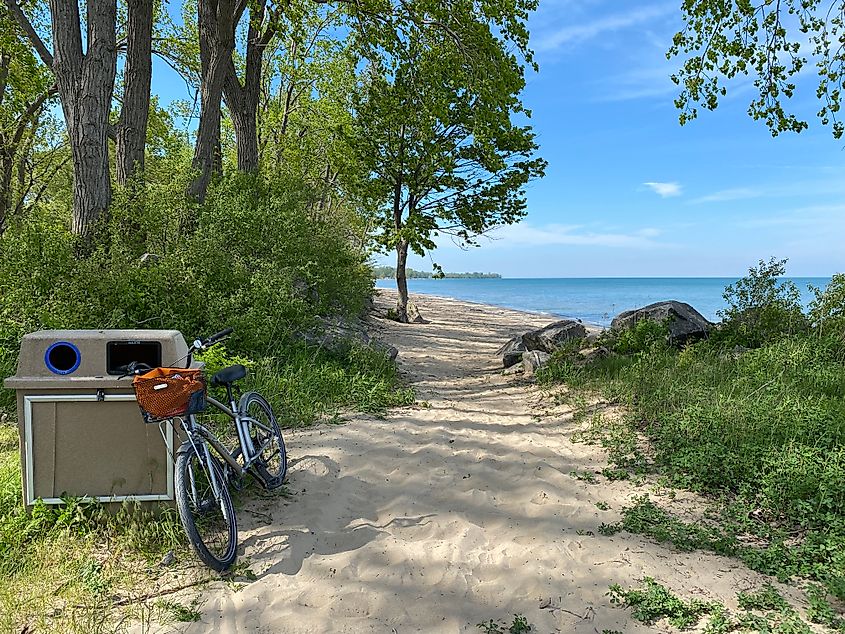 A bike leans up against a public trash can at a beautiful and empty island beach