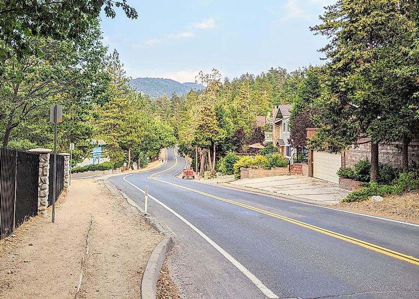 Winding two lane road into Crestline California with green trees lining both sides