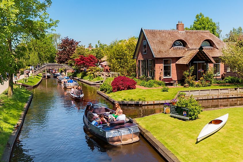 Boats along the canal and quaint Dutch houses in the town of Giethoorn, Netherlands.
