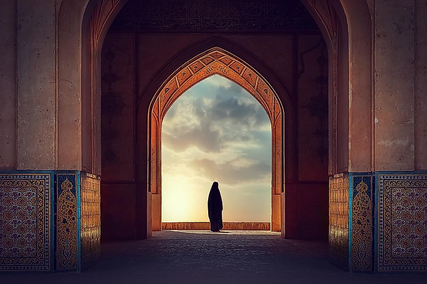 Silhouette of a Persian woman in national dress against the background of traditional Iranian architecture. Sunset. Iran. Kashan.