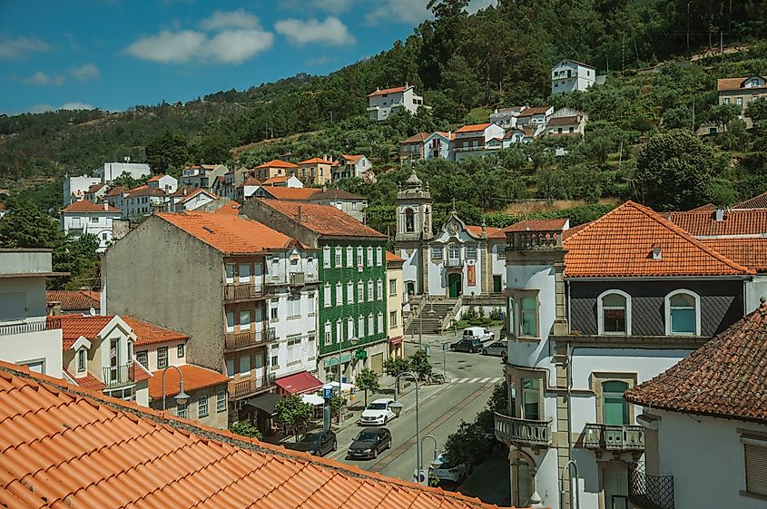 Street with colorful buildings and a baroque church in the hilly town of Seia, Portugal