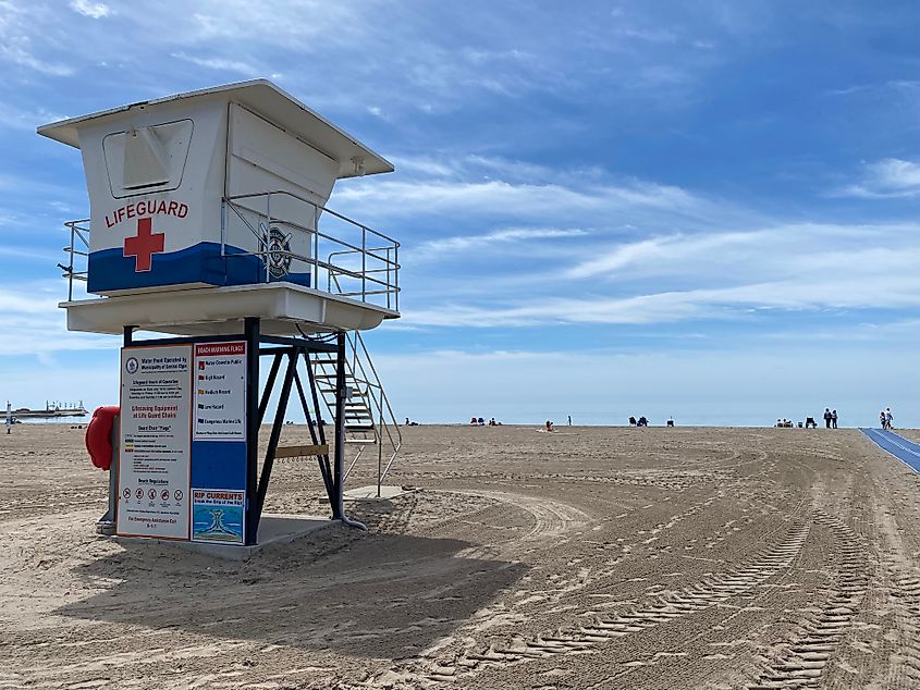 A lifeguard tower stands before a big beach on a bluebird day.