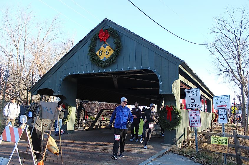 Long Grove, Illinois, USA, November 23, 2023, Runners in the Long Grove Turkey Trot running through the Robert Parker Coffin Covered Bridge with a Christmas wreath on it