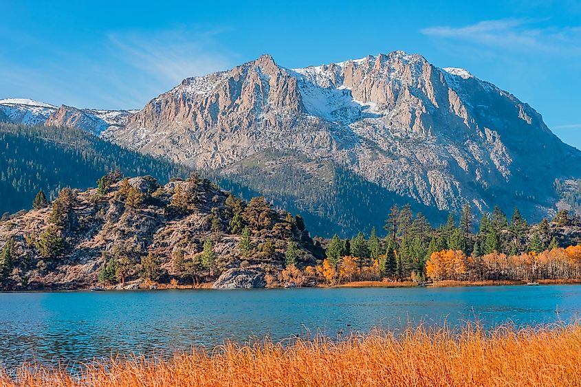 Boaters hug the shoreline of Gull Lake in the Californian Sierra Nevada mountains in autumn.