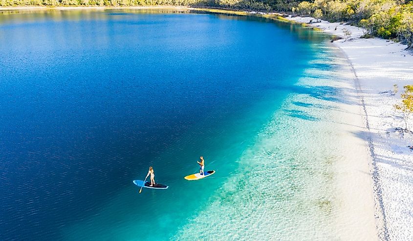 Couple stand-up paddleboarding on Lake McKenzie, K'gari, Queensland, Australia.