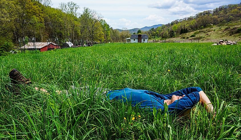 Hiker rests outside on the green grass in Damascus, Virginia.