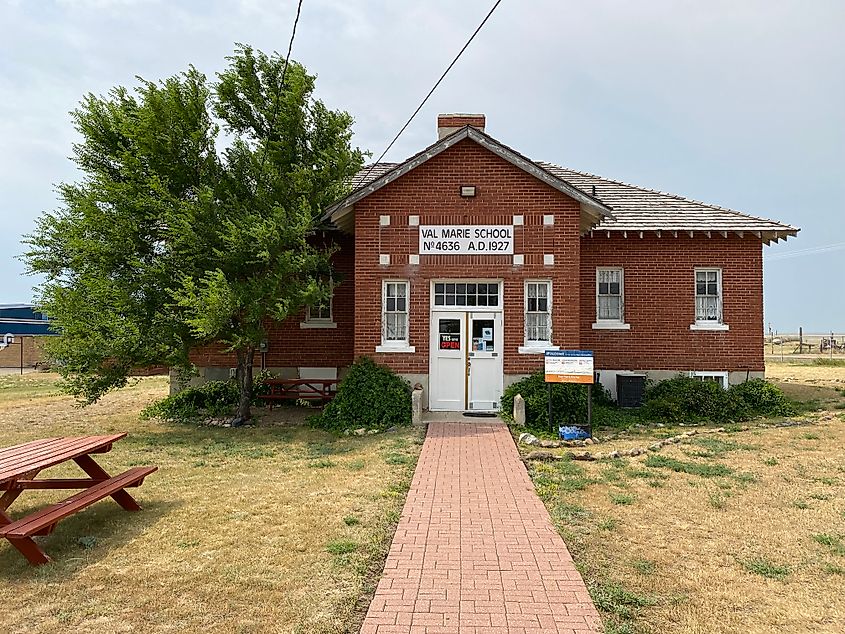 A small brick schoolhouse in the middle of an open field.