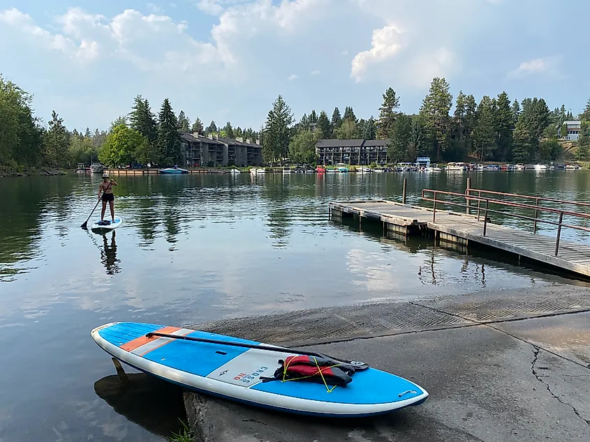 A female stand-up paddleboarder works her way to the dock, where another blue paddleboard is already parked.