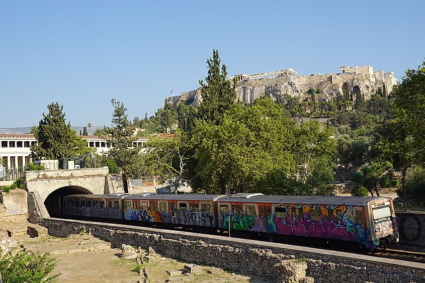 Electric railway carriages, painted with graffiti, pass through the ancient agora. Credit: Fanouria / Shutterstock