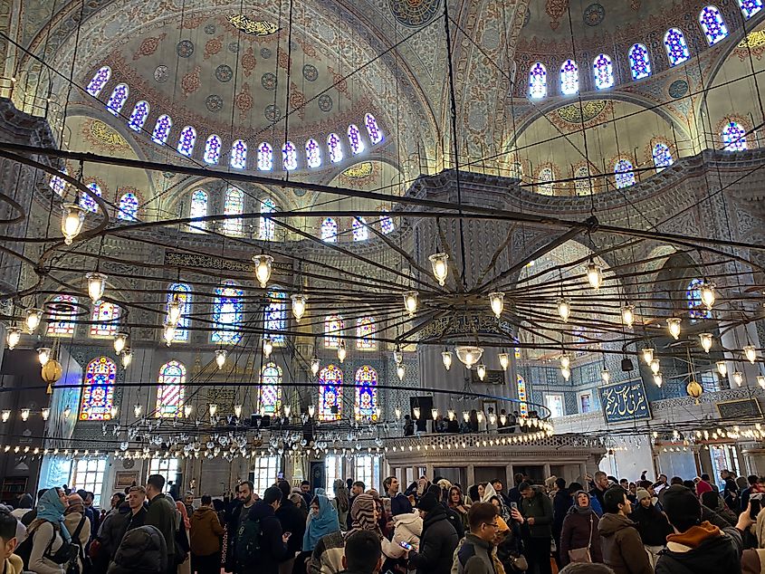 A large crowd gathers within an ornate mosque.