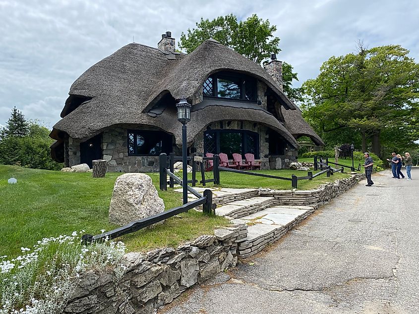 A group of tourists stop to take photos of a large mushroom-shaped dwelling.